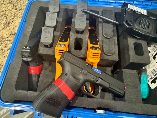 Open blue training case loaded with Glock training pistols, SureStrike laser cartridges, and magazines